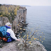 A hiker rests on top of rock cliffs at Lake Michigan